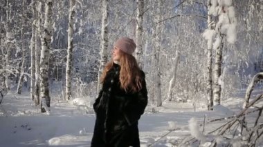Güzel bir kadının mutlu ve parkta bir kış gününde yürür.