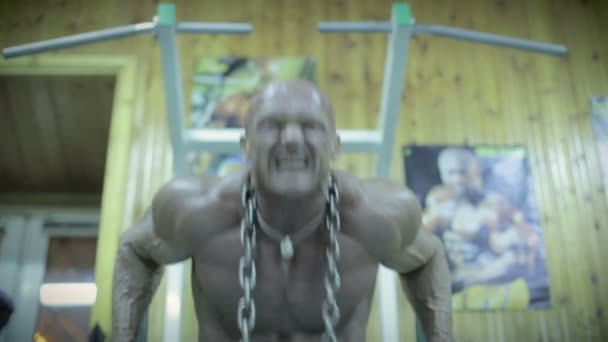 Culturista haciendo flexiones en las barras de ejercicio en el gimnasio . — Vídeos de Stock