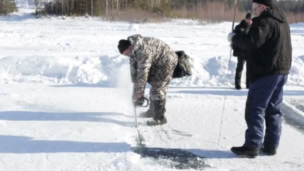Kurgan, RUSSIA - 14 febbraio 2016: Due uomini adulti usano seghe speciali per tagliare il ghiaccio durante la navigazione estrema sul lago ghiacciato in San Valentino nevoso in Russia 14 febbraio 2016 nel sud — Video Stock
