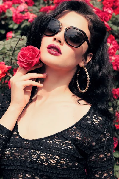 Sensuele vrouw poseren naast rozen — Stockfoto