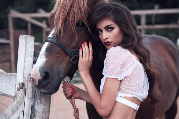 Hermosa joven con el pelo oscuro posando en la granja, con caballo —  Fotos de Stock