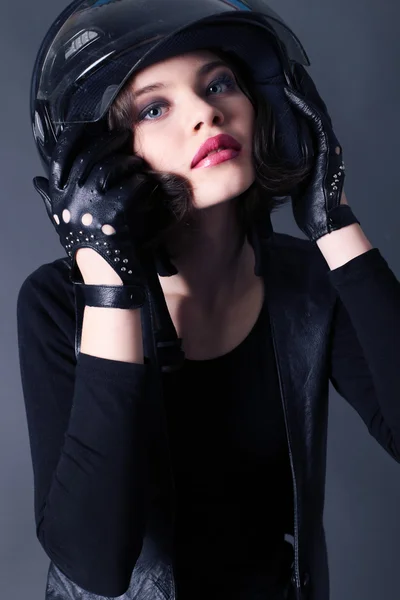 Girl with dark short hair wears biker clothes. leather jacket and helmet — 图库照片