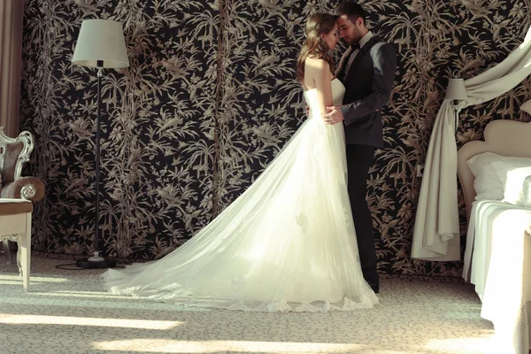 Nádherný pár a nevěsta nosit svatební oblečení, objímat v ložnici — Stock fotografie