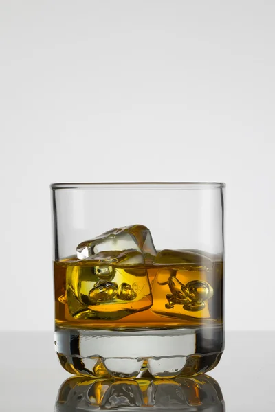 Vaso de whisky con hielo sobre fondo blanco — Foto de Stock