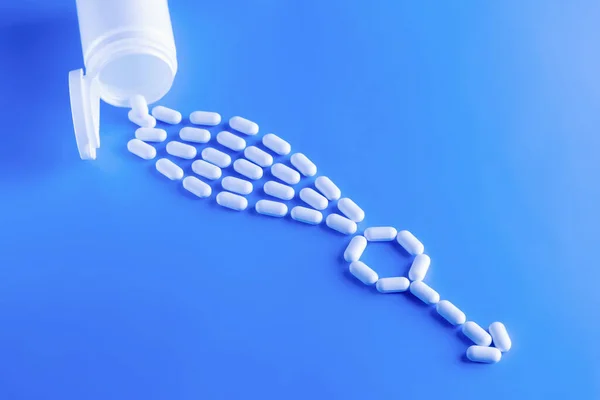 Erectile dysfunction therapy medical concept. Pills are poured out of a bottle and stacked in a male gender symbol on a blue background — Stock Photo, Image