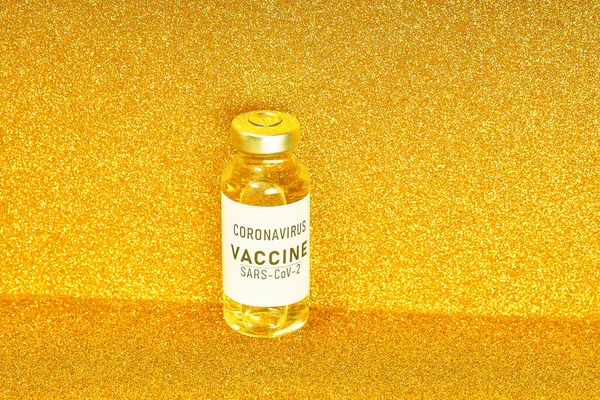 Coronavirusvaccin. Vaccinatiewaarden tijdens de acute periode van het covid-19 pandemische concept. Flacon op een gouden achtergrond. Gouden tong — Stockfoto