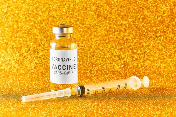 Coronavirusvaccin. Vaccinatiewaarden tijdens de acute periode van het covid-19 pandemische concept. Flacon en spuit op een gouden achtergrond. Gouden tong — Stockfoto