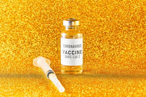 Wachtend op het coronavirus vaccinatie concept. Flacon en spuit op een gouden achtergrond. Gouden tong — Stockfoto