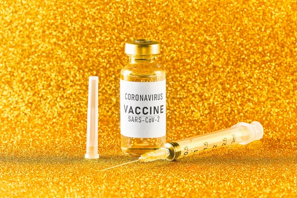 Wachtend op het coronavirus vaccinatie concept. Flacon en spuit op een gouden achtergrond. Gouden tong — Stockfoto