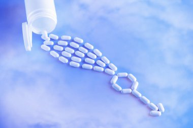 Ereksiyon bozukluğu terapi tıbbi konsepti. Haplar şişeden dökülüyor ve mavi arka planda bir erkek cinsiyet sembolüne konuyor.