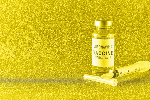 Coronavirusvaccin. Vaccinatiewaarden tijdens de acute periode van het covid-19 pandemische concept. Flacon en spuit op een gouden achtergrond. Gouden tong — Stockfoto