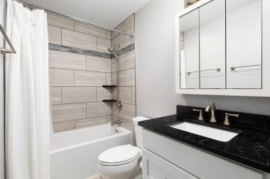 Beyaz bir dolapta siyah mermer tezgah ve kahverengi fayanslarla dolu bir duş..