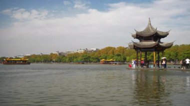 Güneşli bir gün. Hangzhou şehrinin ünlü batı gölü körfezi kalabalık rıhtım pagoda ağır çekim panorama 4k porselen.