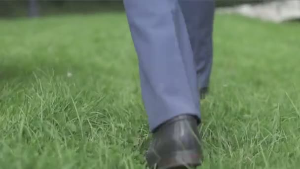 Man in black shoes walking on the lawn — Stock Video