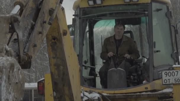 O homem que controla a escavadeira goteja — Vídeo de Stock