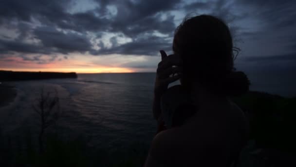 Mulher olhando para o pôr do sol na praia — Vídeo de Stock