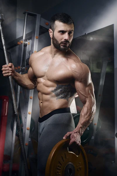 바 벨 무게 플레이트와 함께 서 있는 근육 남자 — 스톡 사진