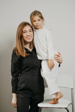 Bir anne bar taburesinde duran kızına sarılıyor. Gülümseyen bir anne ve mutlu bir sarışın çocuk poz veriyor.