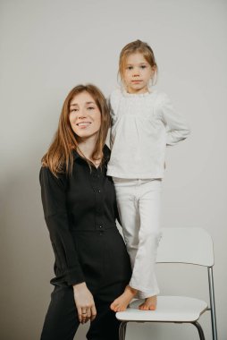 Genç bir anne bar taburesinde duran kızına sarılıyor. Gülümseyen bir anne ve mutlu bir sarışın çocuk poz veriyor.