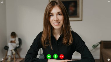 Bir görüntülü konuşma sırasında telekomünikasyon uygulamasının masaüstü bilgisayar ekranı görüntüsü. Bu görüntüde, kızı arkada oynarken kadın iş hakkında rapor veriyor..