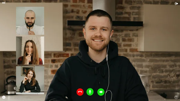 A desktop computer screen view of the telecommunications application during a video conference on which a smiling man is telling about achievements. A multi-ethnic business team in an online meeting.