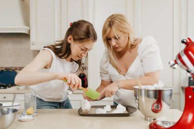 İki genç kadın özenle çırpılmış kremayı bir tepsiye koyuyorlar. Mutfakta bir kaşık ve kürek kemiğiyle. Kızlar lezzetli bir limonlu turta pişirmeye hazırlanıyor..