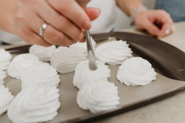 Bir kadının ellerinin fotoğrafı kaşıkla tepside bir çeşit krema yaratıyor. Bir kız lezzetli bir limonlu pasta pişirmeye hazırlanıyor..