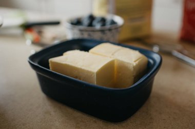 Masanın üzerinde iki parça tereyağı ve mutfaktaki limonlu turta için diğer malzemeler var.