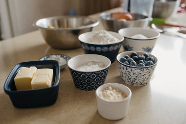 Buğday unu, badem unu, şeker, pudra şekeri, yabanmersini, iki parça tereyağı, nişasta, yumurta, limon mutfakta limonlu turta için hazırlanıyor..