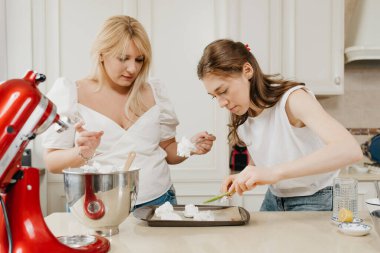 İki genç kadın taze çırpılmış kremayı bir tepsiye koyuyorlar. Mutfakta bir kaşık ve kürek kemiğiyle. Kızlar lezzetli bir limonlu turta pişirmeye hazırlanıyor..
