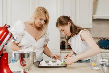 İki genç kadın, çırpılmış kremayı bir tepsiye, kaşıkla ve kürek kemiğiyle itinayla koyuyorlar. Kızlar lezzetli bir limonlu turta pişirmeye hazırlanıyor..