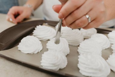 Bir kadının ellerinin fotoğrafı kaşıkla tepside bir çeşit krema yaratıyor. Bir kız lezzetli bir limonlu pasta pişirmeye hazırlanıyor..