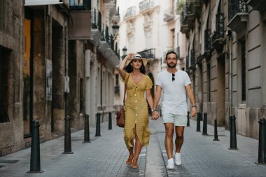 Şapkalı ve sarı yakalı bir kız ve sakallı erkek arkadaşı İspanya 'nın eski kasabasında el ele tutuşuyorlar. Valencia 'da randevusu olan iki turist..