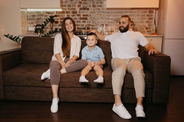 Baba, oğul ve anne evdeki kanepede televizyon izliyorlar. Mutlu aile akşamın tadını çıkarıyor. Memleketteki akrabalar. Uzun saçlı genç bir anne gülüyor..