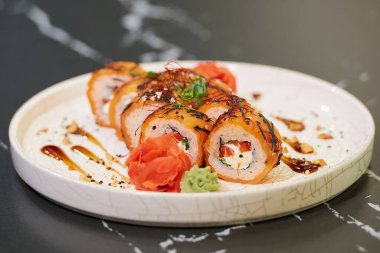 Somon balıklı, Philadelphia peynirli, ton balıklı, soslu, fıstıklı, zencefilli ve wasabi peynirli suşi rulolarının yakın plan fotoğrafı..