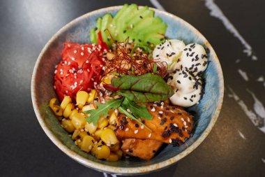 Üzerinde ton balığı, avokado dilimleri, wasabi, mısır, fıstık, susam ve Philadelphia peyniri olan bir poke kasesi..