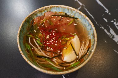 Geleneksel Japon çorbasının üst görüntüsü yumurtalı Ramen ve domuz eti mavi bir seramik kasede siyah taş bir masada..