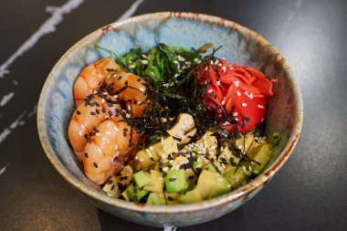 Chuka Wakame deniz yosunu, wasabi, avokado, kaju, nori ve karidesli siyah taş bir masa..