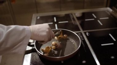 İçinde kaynar yağ olan hareketli bir video. Mutfaktaki ahtapotları hareket ettiren forseps ile aşçının eli..