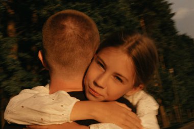 Gölün kıyısında babasına sarılan genç bir kızın bulanık bir fotoğrafı var. Günbatımında tatilde olan tek ebeveynli aile.