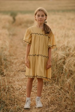 Çavdar tarlasının ortasında gün batımında elbise giymiş genç bir kızın tam boy portresi..