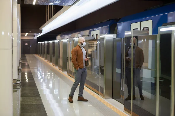 코로나 바이러스가 퍼지지 않도록 의료용 마스크를 남자가 지하철에서 열차를 기다리는 — 스톡 사진