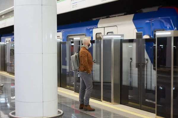 코로나 바이러스가 퍼지지 않도록 의료용 마스크를 남자가 지하철 승강장에서 열차를 — 스톡 사진