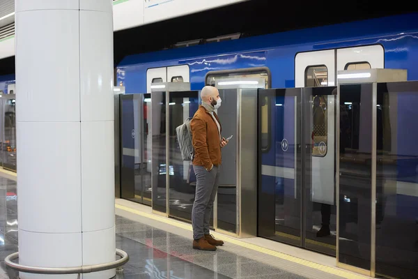 코로나 바이러스가 퍼지는 피하기 마스크를 남자가 지하철 승강장에서 현대식 열차를 — 스톡 사진