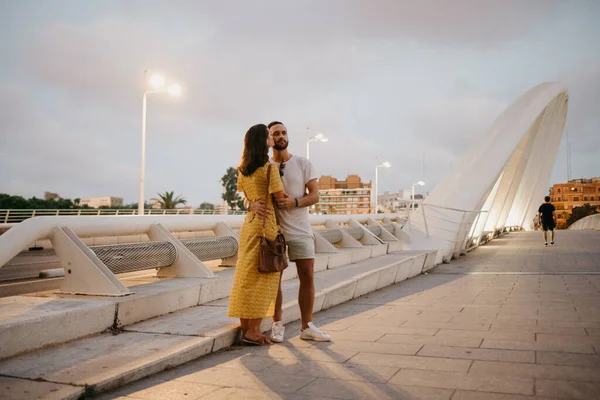 Brunetka Žlutých Šatech Její Usmívající Přítel Objímají Bílém Mostě Valencii — Stock fotografie