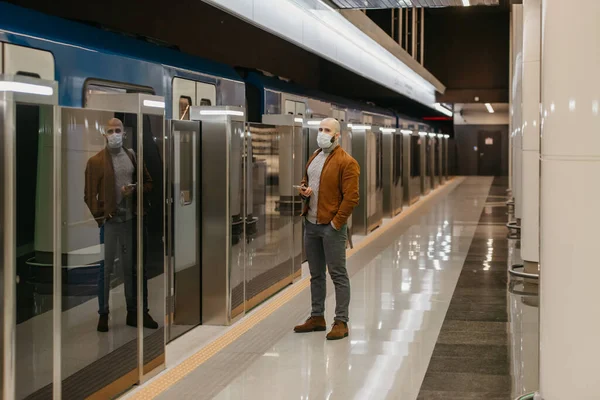 코로나 바이러스가 퍼지지 않도록 의료용 마스크를 남자가 지하철에서 열차를 기다리는 — 스톡 사진