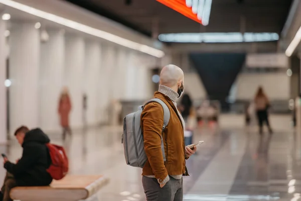 의료용 마스크를 남자가 스마트폰을 지하철 중앙에서 열차를 기다리며 주변을 둘러보고 — 스톡 사진