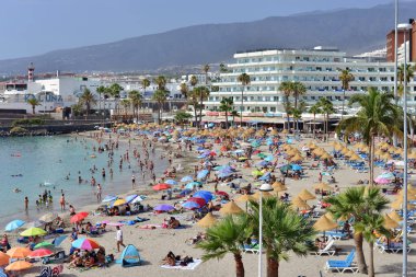 Costa Adeje, Tenerife, Kanarya Adaları, İspanya - 27 Temmuz 2025: Tatilcilerle La Pinta plajı manzarası. Sıcak yaz günü.