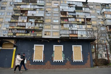 Kyiv, Ukrayna - 21 Aralık 2025: Bir çift, 29 Kasım 2025 'te Rus füze saldırısı sonucu camları hasarlı bir evin önünden geçtiler.