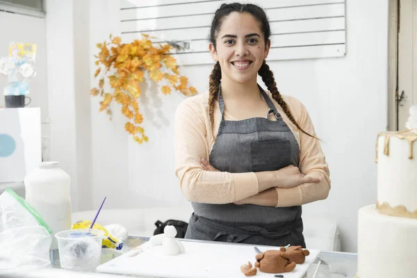 Pasta dükkanında gururlu bir Latin kadın. Kollarını kavuşturup pasta atölyesindeki kameraya bakan kadın. Girişimci İspanyol kadın.